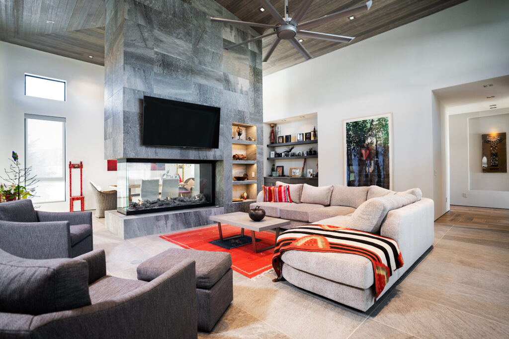 BJD custom home living room with floor-to-ceiling, 3-sided fireplace with grey porcelain tiles. 