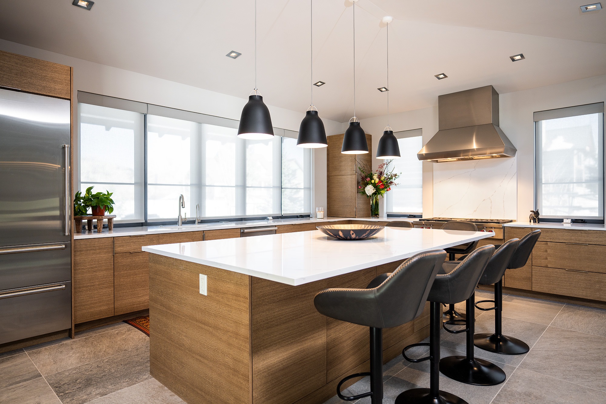 BJD custom home kitchen angled shot with barstools and black pendants